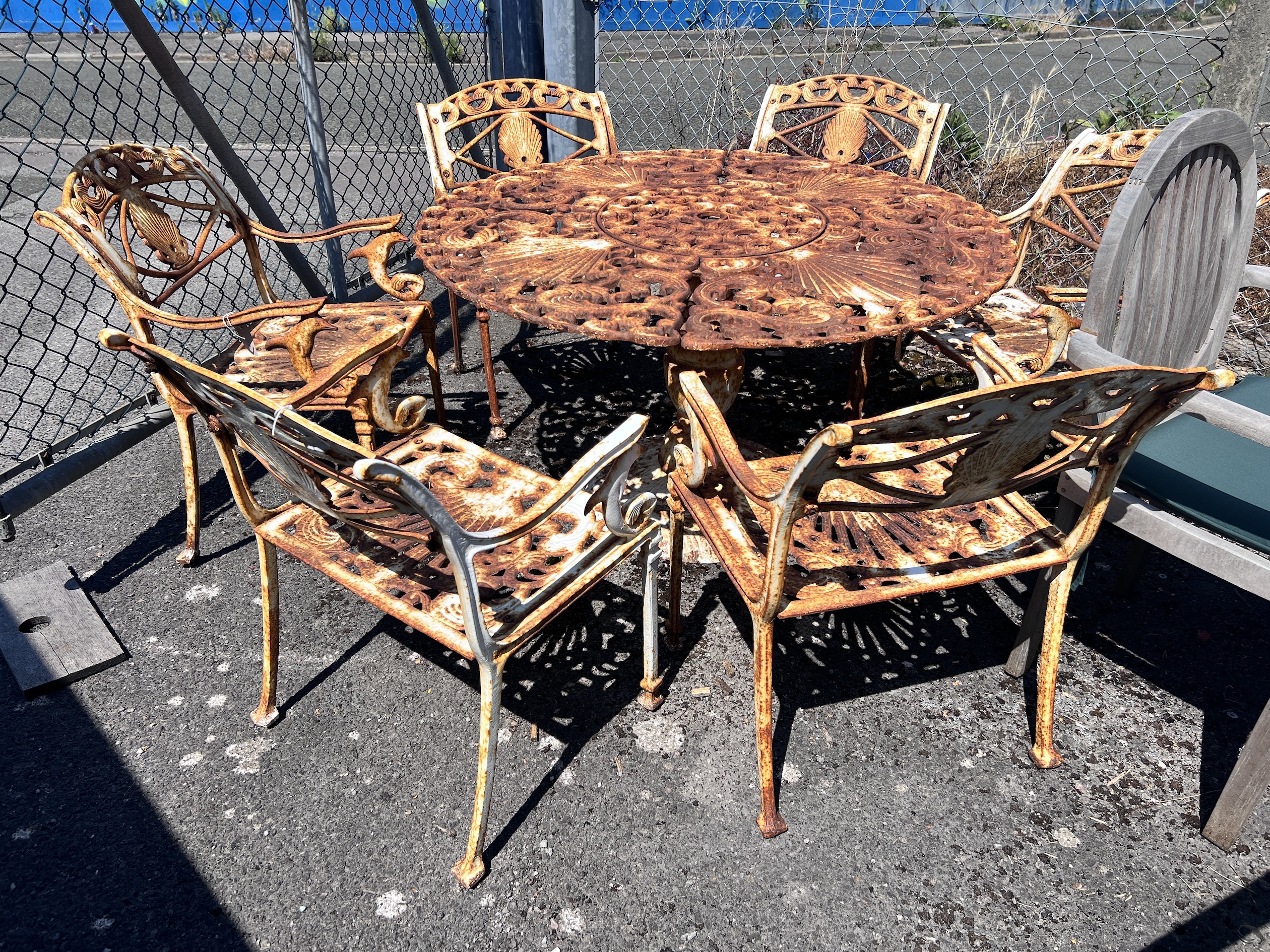 A Victorian style circular painted cast iron garden table, diameter 20cm, height 66cm and six chairs, cast with scallop shells and dolphins